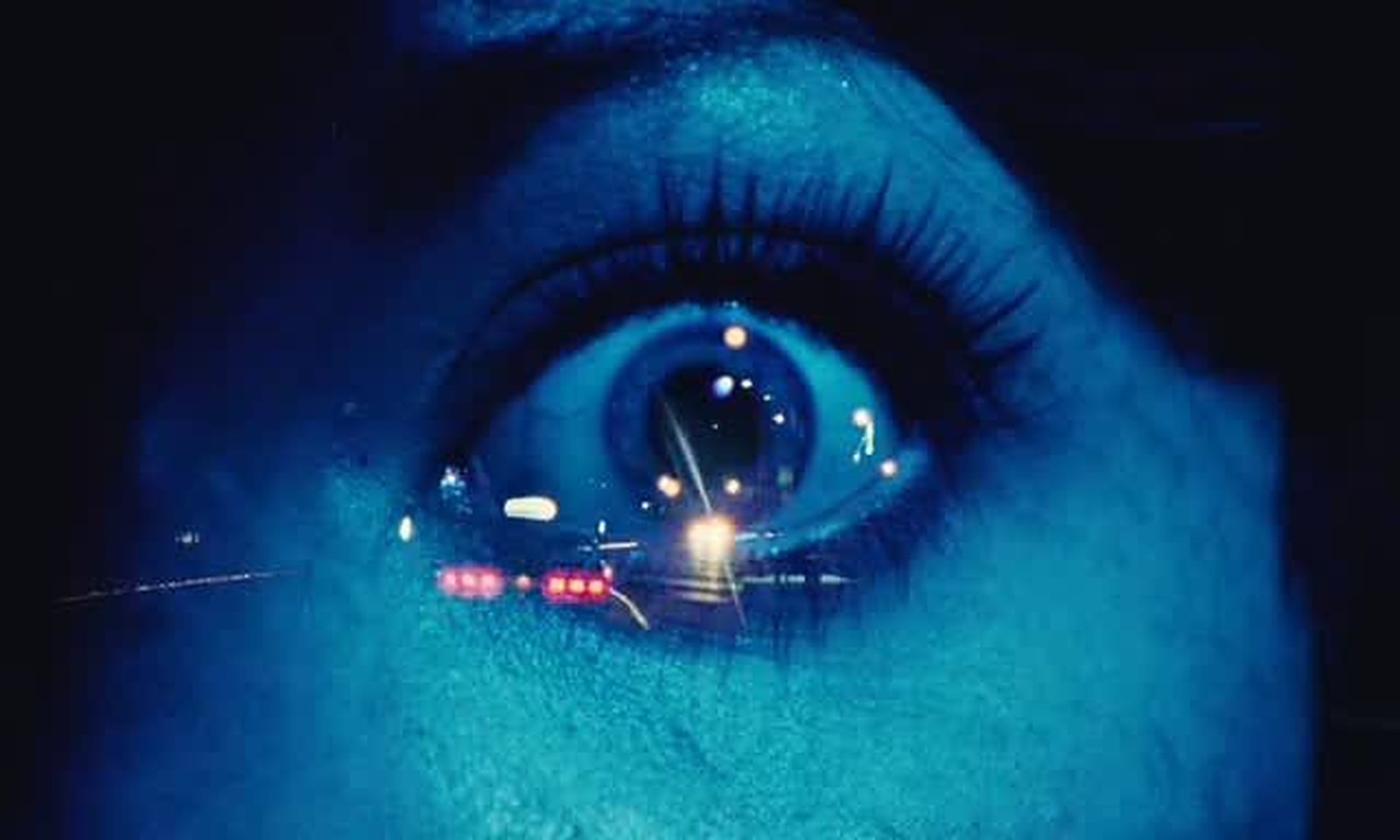 The Thousand Deaths of the Cranefly: extreme close-up of a wide, blue-lit eye with blurred city lights reflected in it